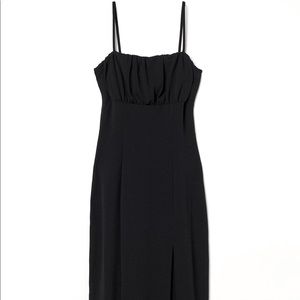 Black fitted dress with spaghetti straps and high slit.